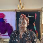 Artist standing in front of colorful art.